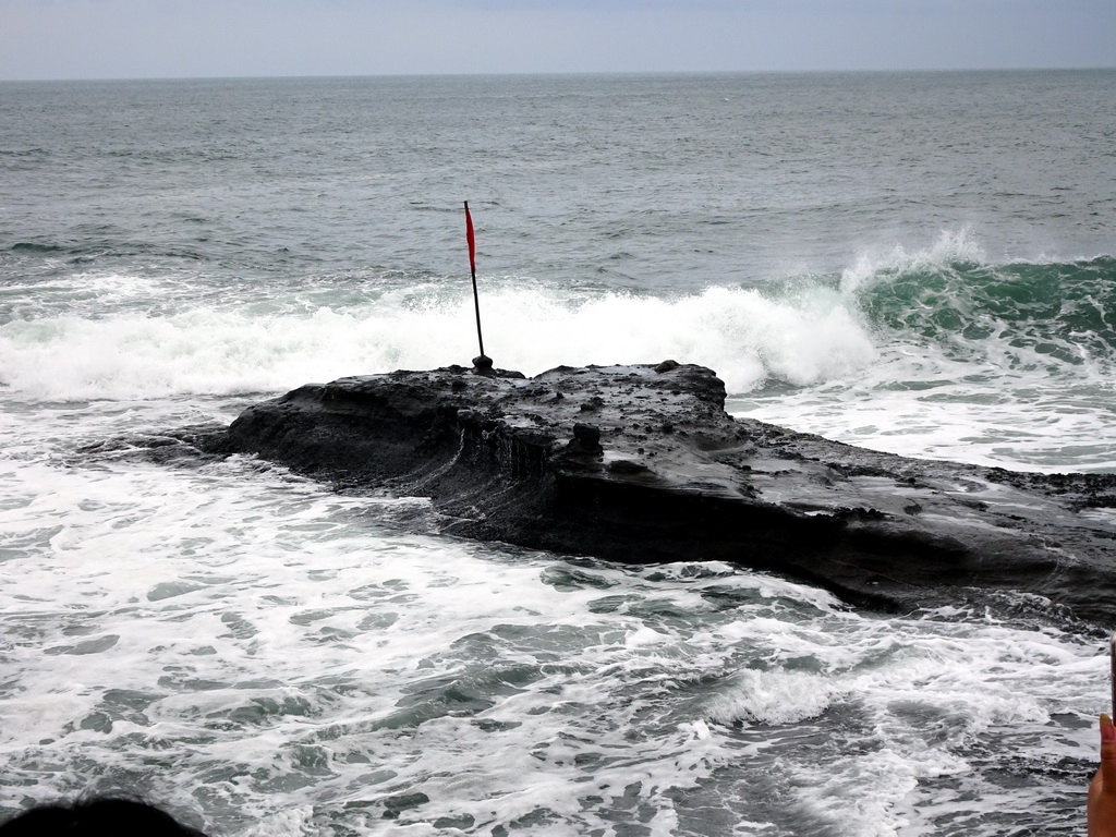 Small island with flag, viewed from the shore at the Pura Luhur Penataran temple