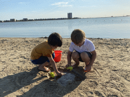 Max and his friend playing with toys and sand at the beach at the Binnenschelde lake, with a view on the Mayflower Holding building