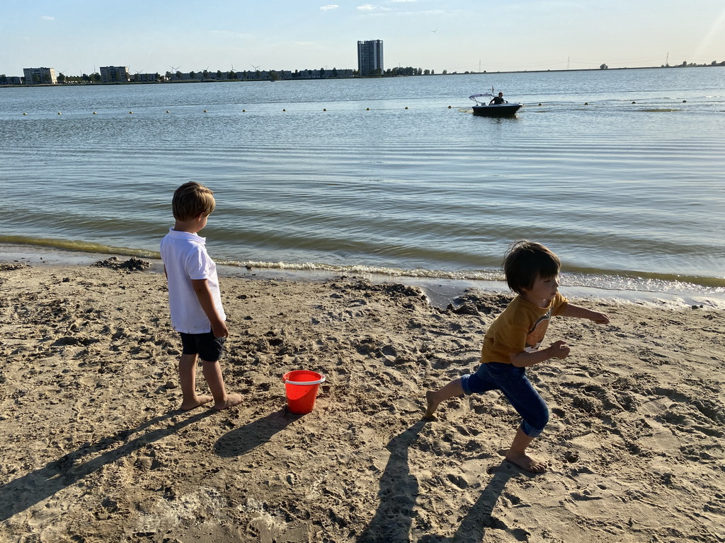 Max and his friend at the beach at the Binnenschelde lake, with a view on the Mayflower Holding building