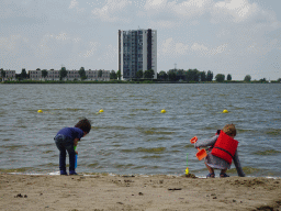 Max and his friend at the beach at the Binnenschelde lake, with a view on the Mayflower Holding building