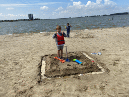 Max and his friend building a sand castle at the beach at the Binnenschelde lake, with a view on the Mayflower Holding building