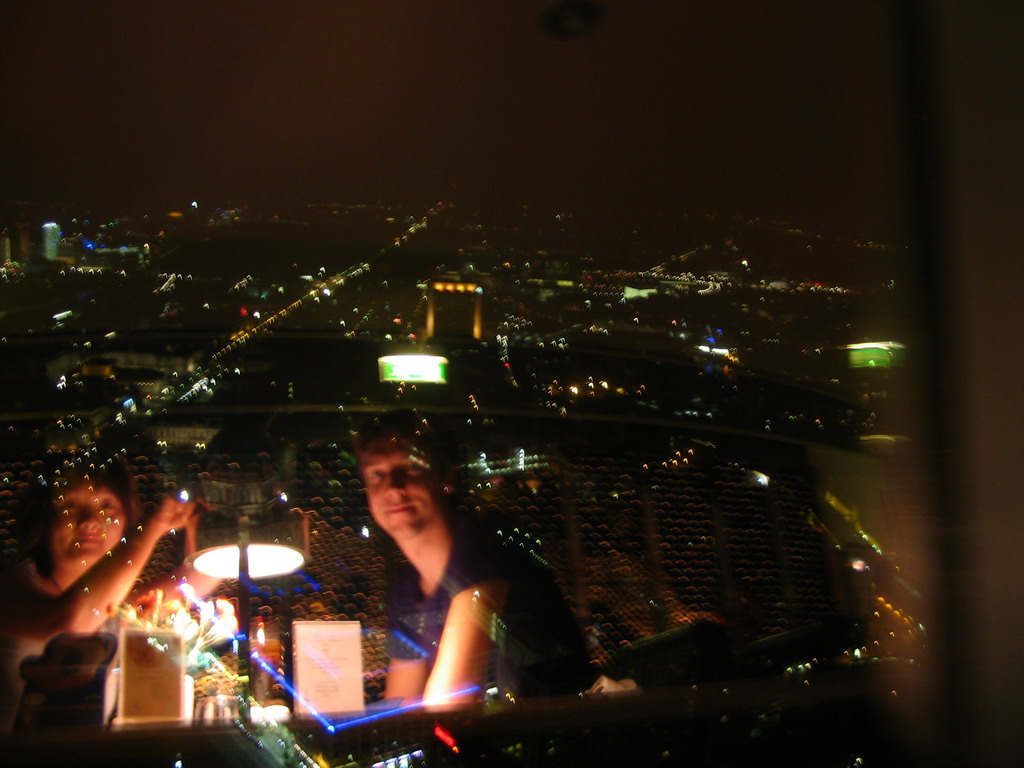 West side of the city, viewed from the Telecafé restaurant on top of the Fernsehturm tower, with a reflection of Tim and Miaomiao having dinner, by night