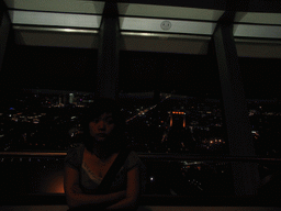 Miaomiao at the viewing point on top of the Fernsehturm tower, with a view on the west side of the city, by night