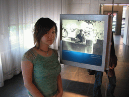 Miaomiao with a photograph of someone building the Berlin Wall, at the Gedenkstätte Berliner Mauer museum
