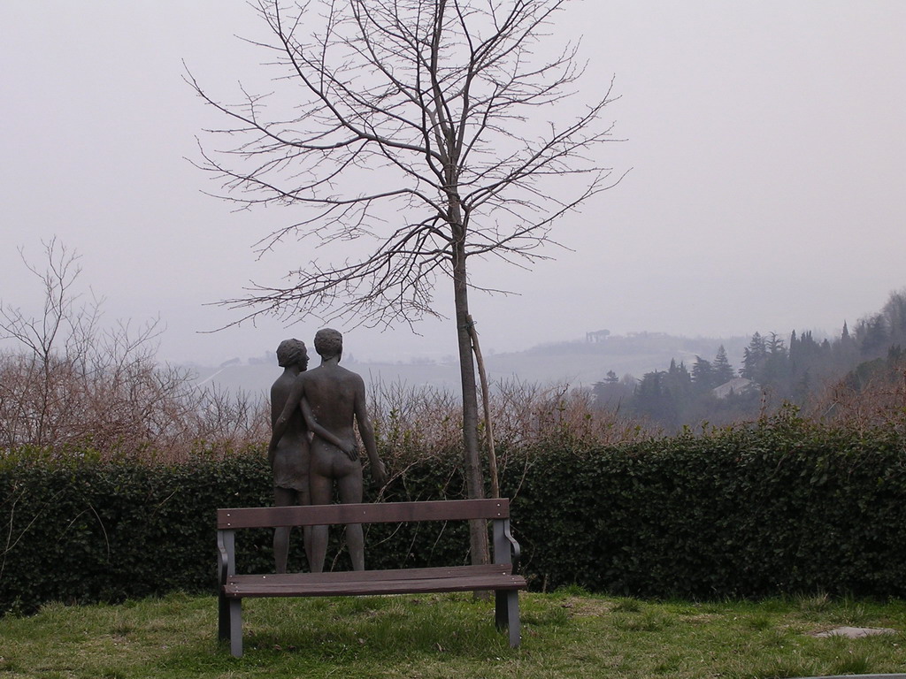 Statue and bench at the southwest side of the La Rocca castle, with a view on the hills around the town