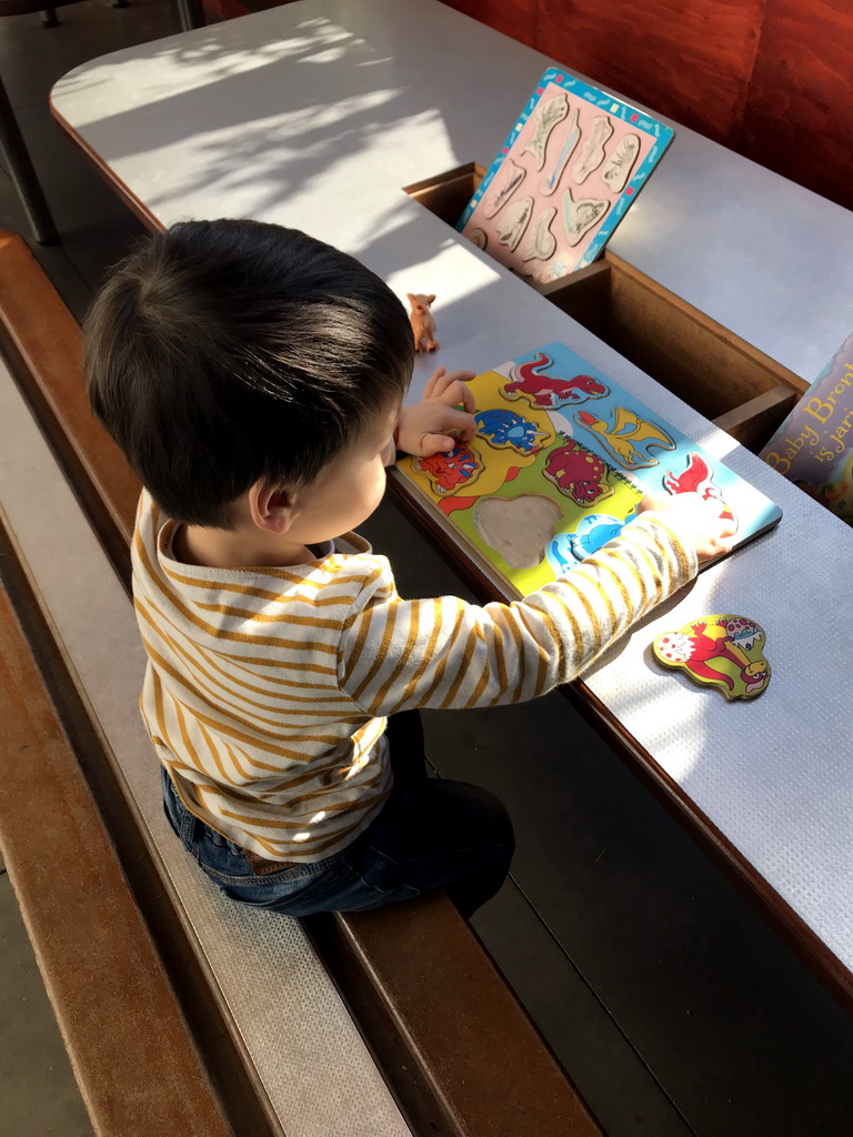 Max playing with a puzzle in the hallway from the Dinohal building to the Museum building of the Oertijdmuseum