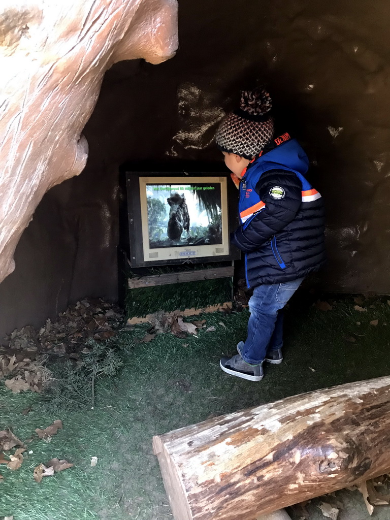 Max and a television screen in a prehistoric hut in the Oertijdwoud forest of the Oertijdmuseum