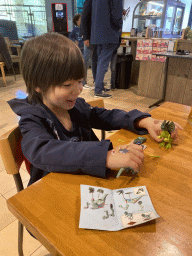 Max playing with his Dilophosaurus and Velociraptor toys at the restaurant at the Lower Floor of the Dinohal building of the Oertijdmuseum