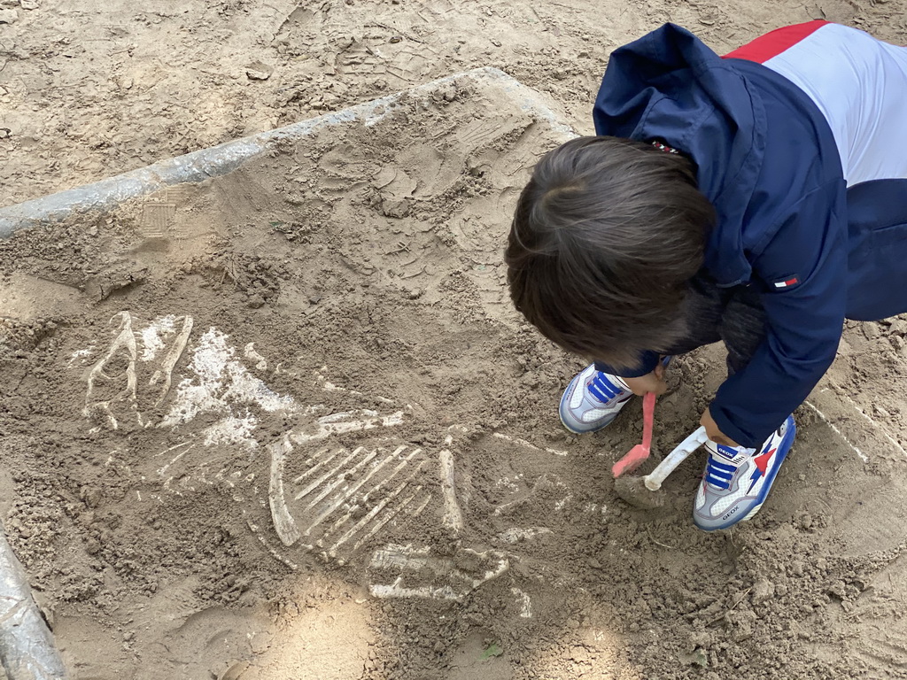 Max with brushes at the dinosaur excavation sandbox at the Oertijdwoud forest of the Oertijdmuseum
