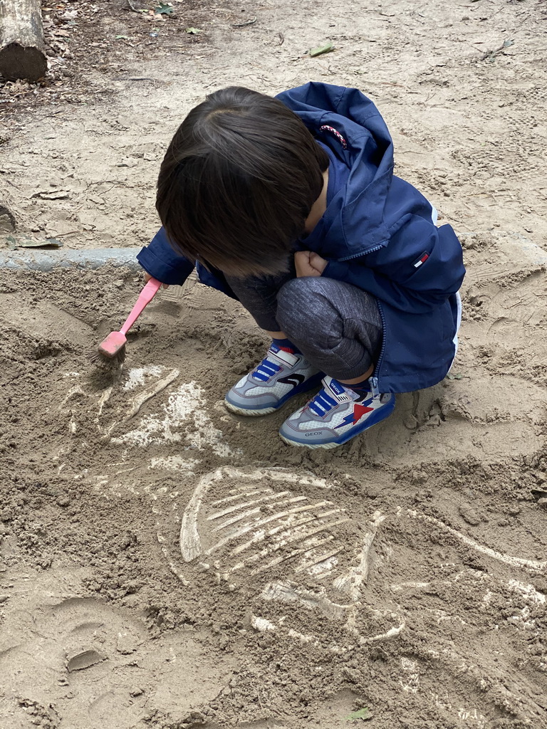 Max with a brush at the dinosaur excavation sandbox at the Oertijdwoud forest of the Oertijdmuseum