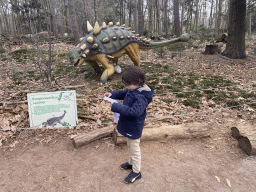 Max with the paper of the scavenger hunt and a statue of an Euoplocephalus, with explanation
