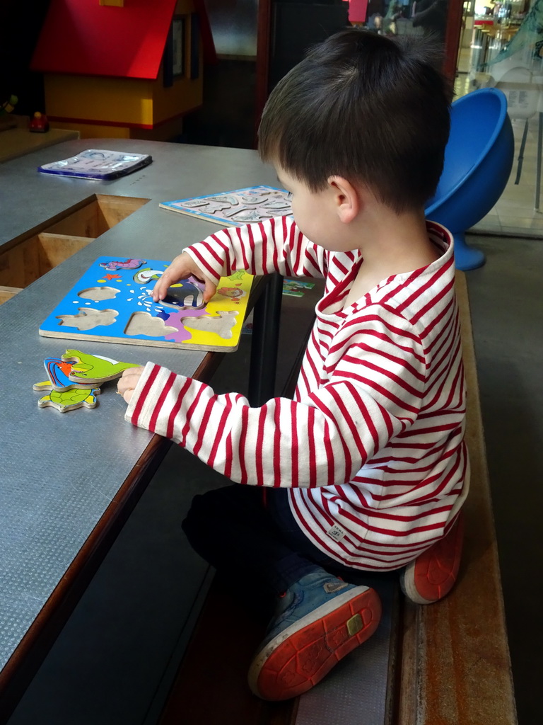 Max playing with a puzzle in the hallway from the Dinohal building to the Museum building of the Oertijdmuseum