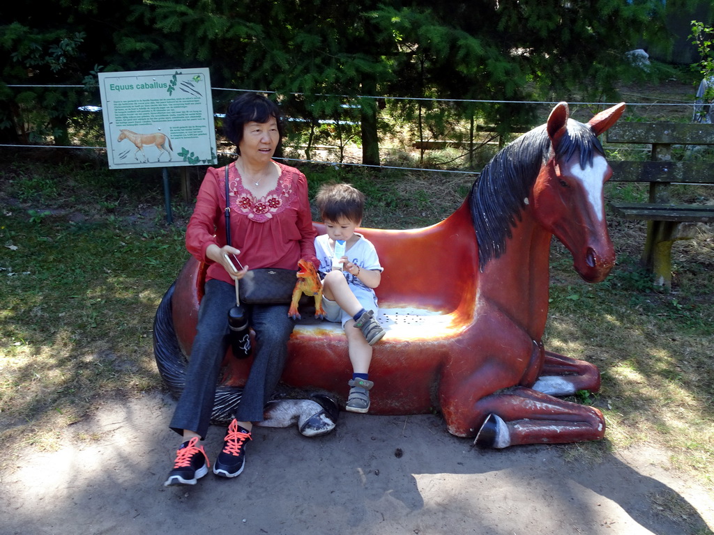 Max and his grandmother on a statue of a Horse at the playground in the Oertijdwoud forest of the Oertijdmuseum