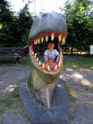 Max with a dinosaur toy in a statue of the head of a Dinosaur at the playground in the Oertijdwoud forest of the Oertijdmuseum