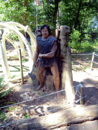 Miaomiao`s mother with a statue of a caveman in the Oertijdwoud forest of the Oertijdmuseum