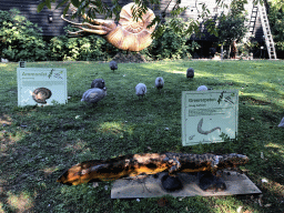 Guineafowls and statues of an Ammonite and a Greererpeton in the Garden of the Oertijdmuseum, with explanation
