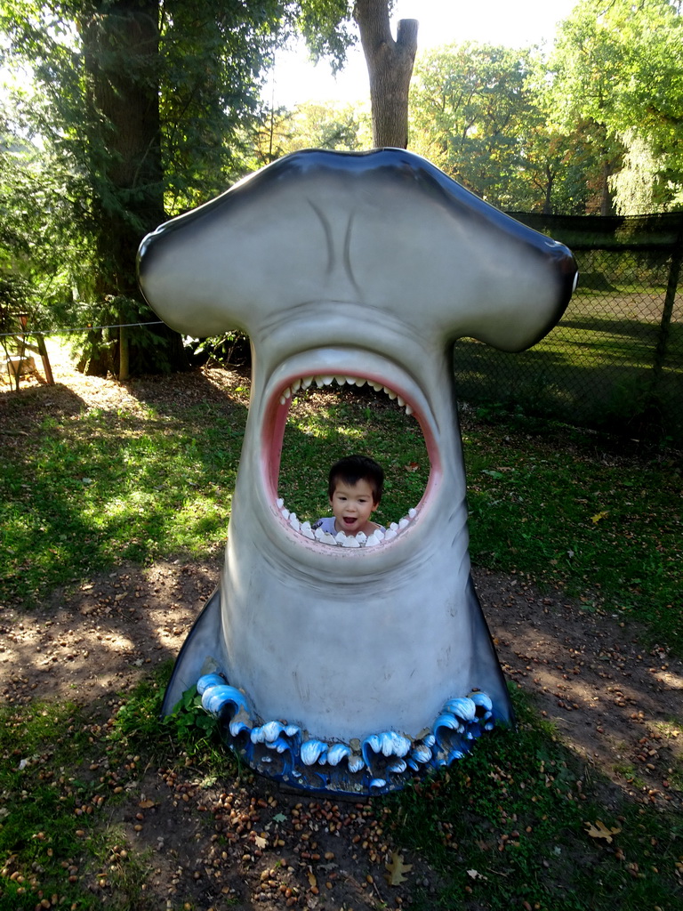 Max in a statue of the head of a Hammerhead Shark at the playground in the Oertijdwoud forest of the Oertijdmuseum