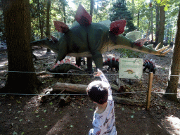 Max with a Stegaosaurus toy and statues of Stegosauruses in the Oertijdwoud forest of the Oertijdmuseum, with explanation