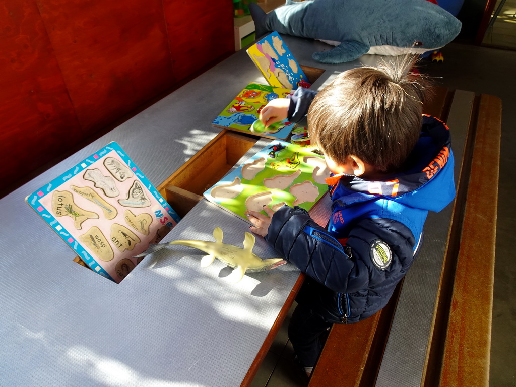 Max playing with a puzzle in the hallway from the Dinohal building to the Museum building of the Oertijdmuseum