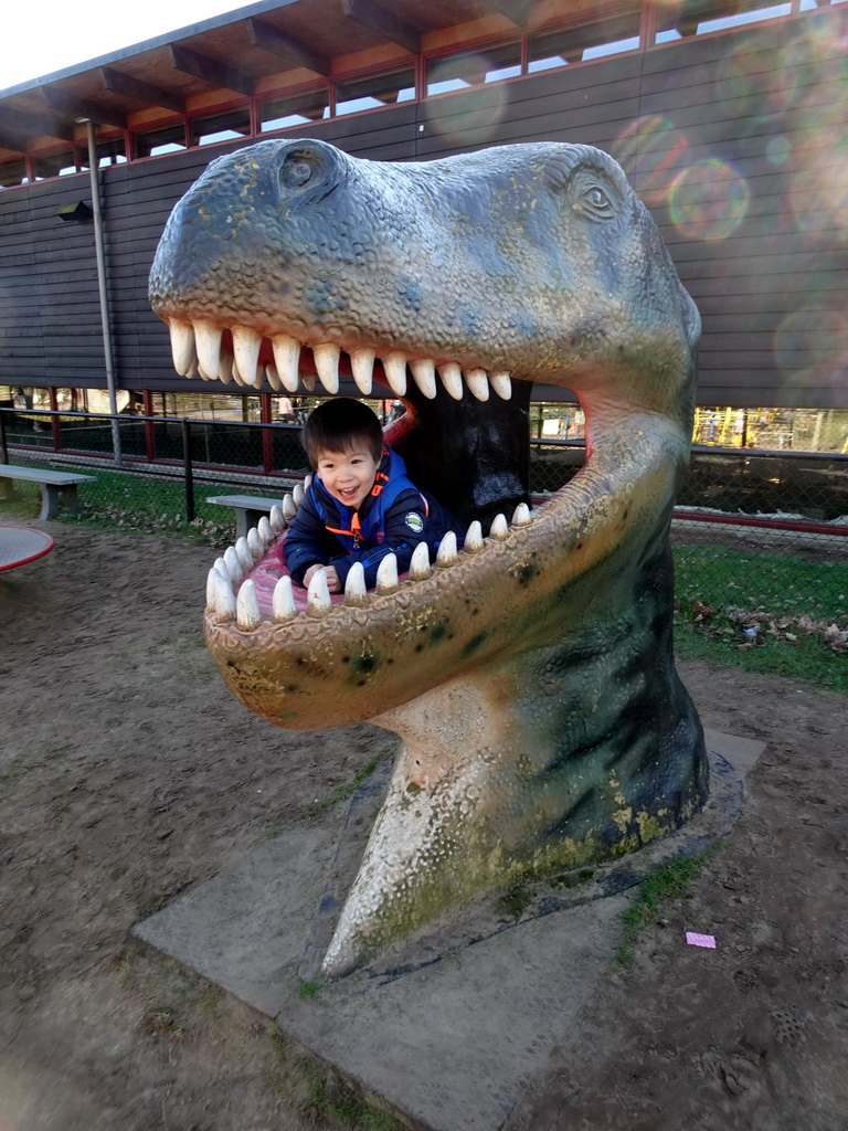 Max in a statue of the head of a Dinosaur at the playground in the Garden of the Oertijdmuseum