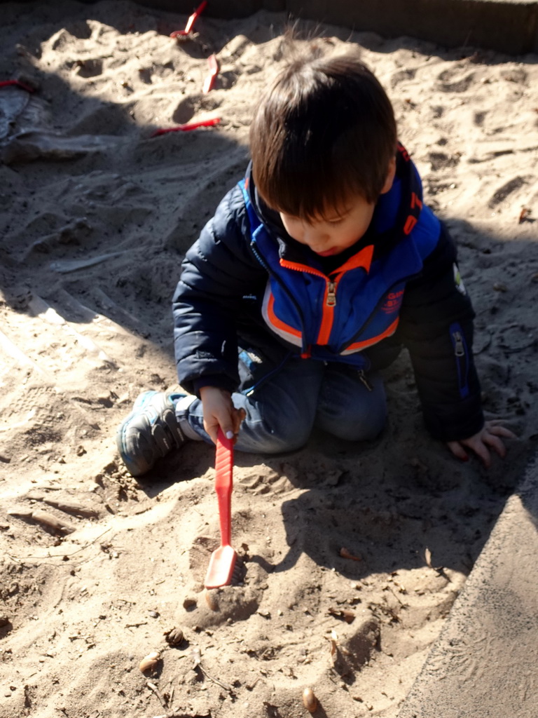 Max with a brush at the dinosaur excavation sandbox at the Oertijdwoud forest of the Oertijdmuseum