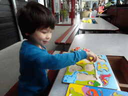 Max playing with a puzzle in the hallway from the Dinohal building to the Museum building of the Oertijdmuseum