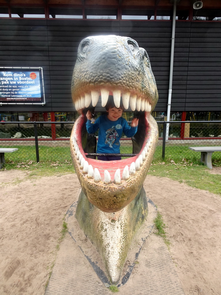 Max in a statue of the head of a Dinosaur at the playground in the Garden of the Oertijdmuseum