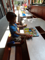 Max playing with a puzzle in the hallway from the Dinohal building to the Museum building of the Oertijdmuseum