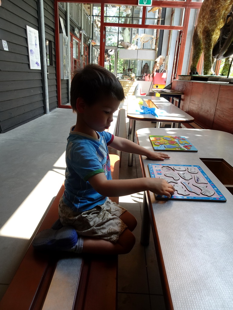 Max playing with a puzzle in the hallway from the Dinohal building to the Museum building of the Oertijdmuseum