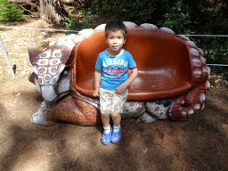 Max sitting on a bench in the shape of an Ankylosaurus in the Oertijdwoud forest of the Oertijdmuseum