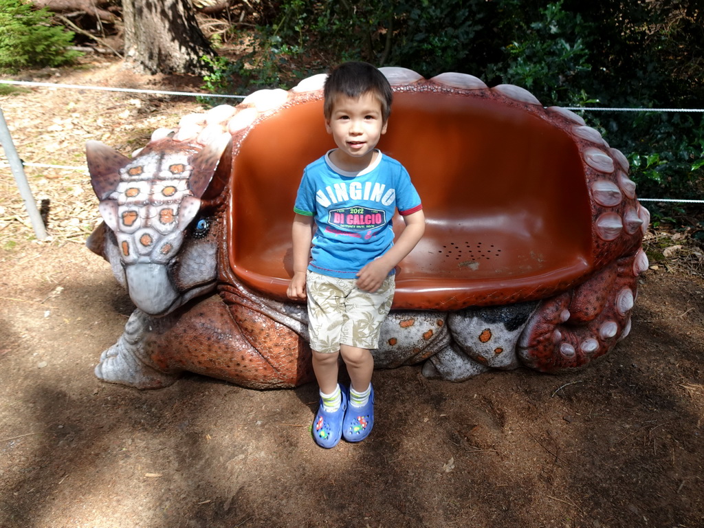 Max sitting on a bench in the shape of an Ankylosaurus in the Oertijdwoud forest of the Oertijdmuseum