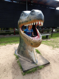 Max in a statue of the head of a Dinosaur at the playground in the Garden of the Oertijdmuseum