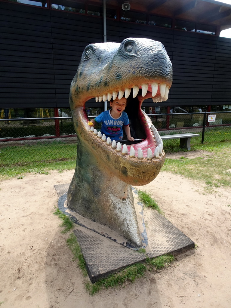 Max in a statue of the head of a Dinosaur at the playground in the Garden of the Oertijdmuseum