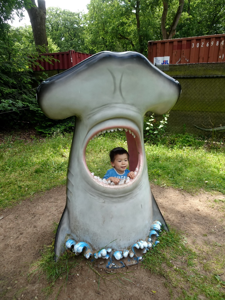 Max in a statue of the head of a Hammerhead Shark at the playground in the Oertijdwoud forest of the Oertijdmuseum