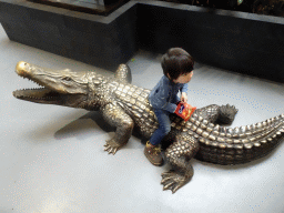 Max on a crocodile statue at the lower floor of the Reptielenhuis De Aarde zoo