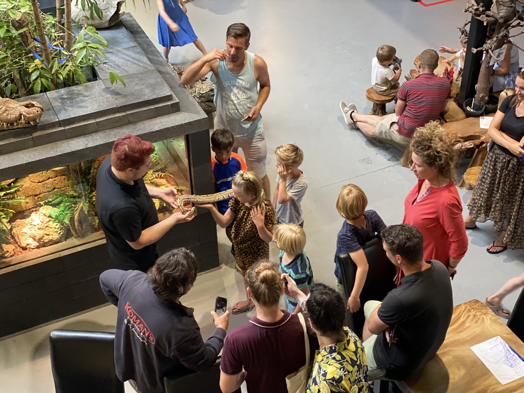 Zookeeper with a Ball Python at the lower floor of the Reptielenhuis De Aarde zoo, viewed from the upper floor