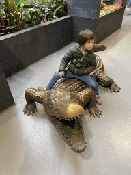 Max on a Crocodile statue at the lower floor of the Reptielenhuis De Aarde zoo