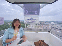 Miaomiao with wine in our capsule at the Smakenrad ferris wheel at the Chasséveld square, with a view on the Stadskantoor building and the Chassé Theater