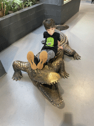 Max on a Crocodile statue at the lower floor of the Reptielenhuis De Aarde zoo