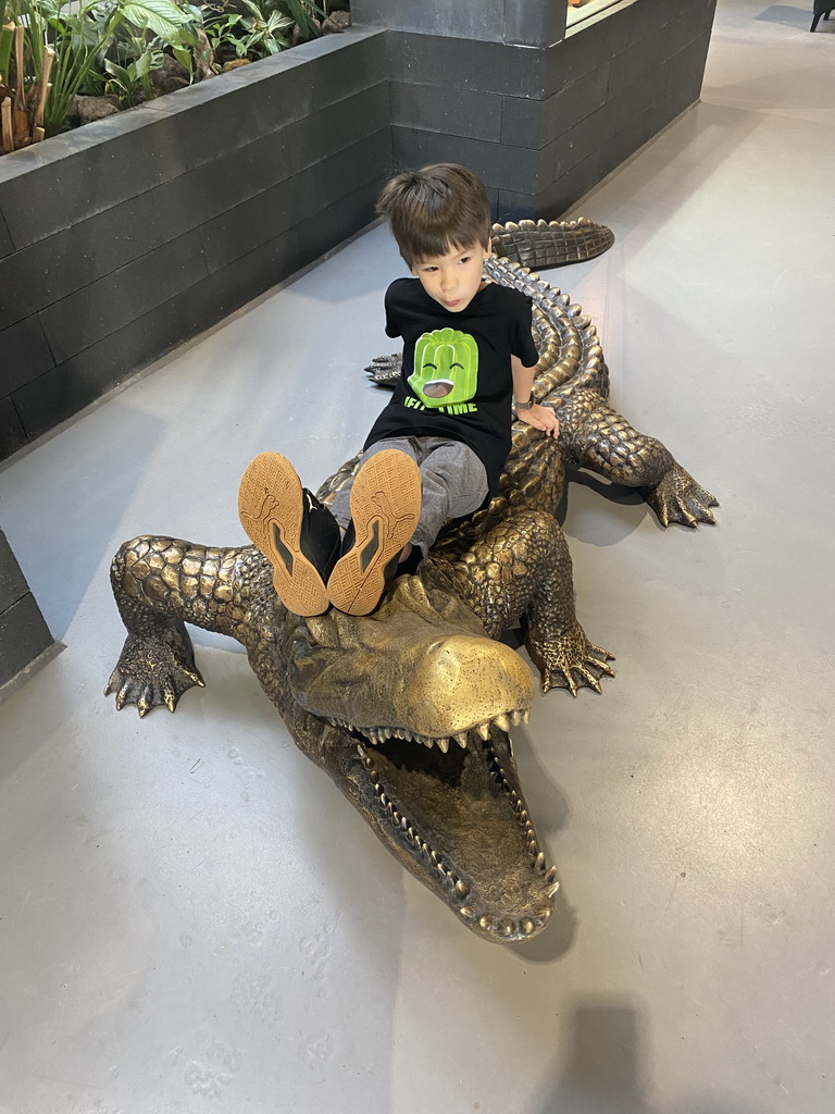 Max on a Crocodile statue at the lower floor of the Reptielenhuis De Aarde zoo