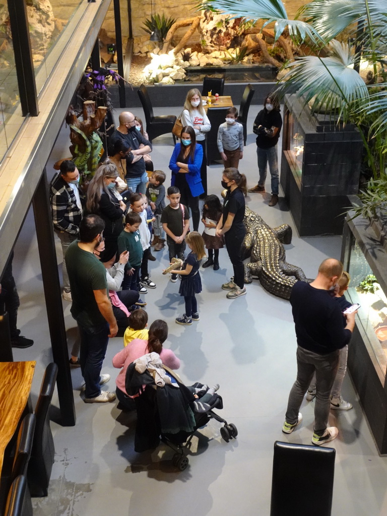 Zookeeper with a Ball Python at the lower floor of the Reptielenhuis De Aarde zoo, viewed from the upper floor