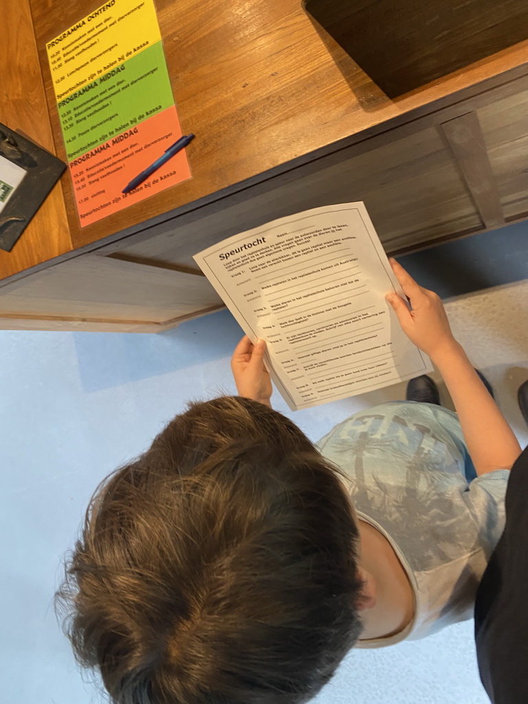 Max with questions on the paper of the scavenger hunt at the cash desk of the Reptielenhuis De Aarde zoo