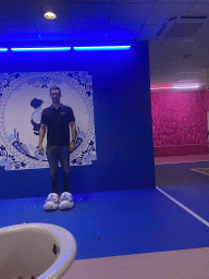 Tim with wooden shoes in front of a Delfts Blauw painted tile at the SuperNova Experience museum