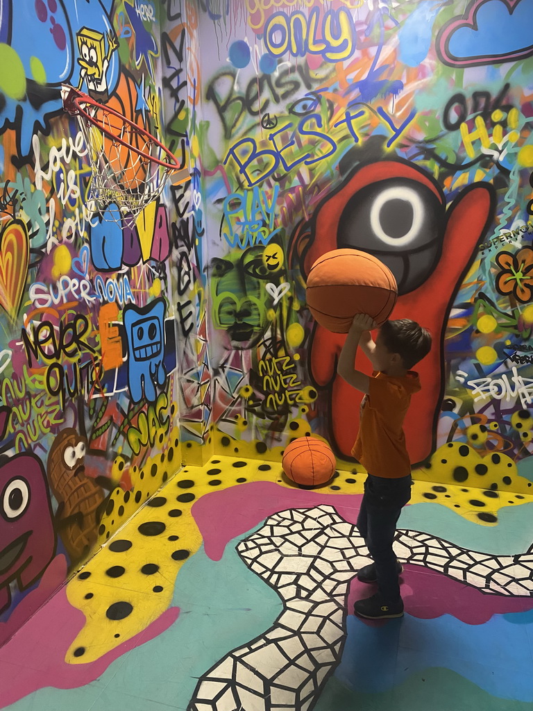 Max throwing a basketball at the graffiti room at the SuperNova Experience museum