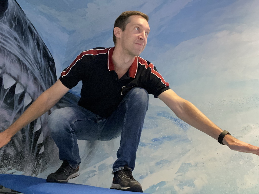 Tim surfing in front of a shark at the SuperNova Experience museum