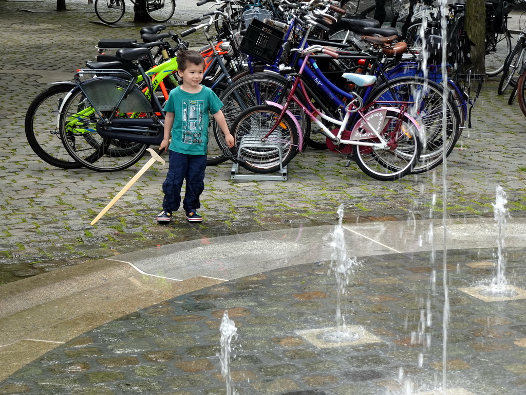 Max with a wooden sword playing with the fountain at the Kasteelplein square, during the Nassaudag