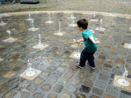 Max with a wooden sword playing with the fountain at the Kasteelplein square, during the Nassaudag