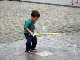 Max with a wooden sword playing with the fountain at the Kasteelplein square, during the Nassaudag