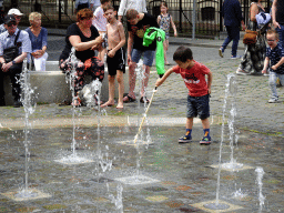 Max with a wooden sword playing with the fountain at the Kasteelplein square, during the Nassaudag