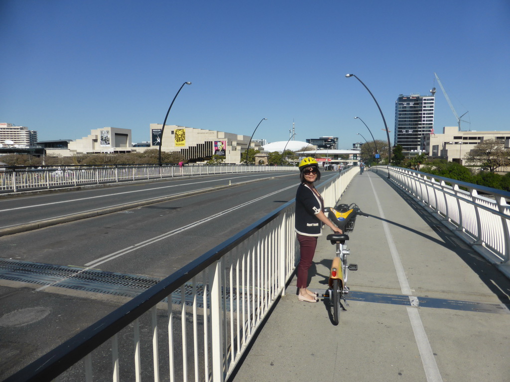 Miaomiao with her CityCycle bicycle on the Victoria Bridge over the Brisbane River, with a view on the Queensland Performing Arts Centre and the Queensland Museum & Sciencentre